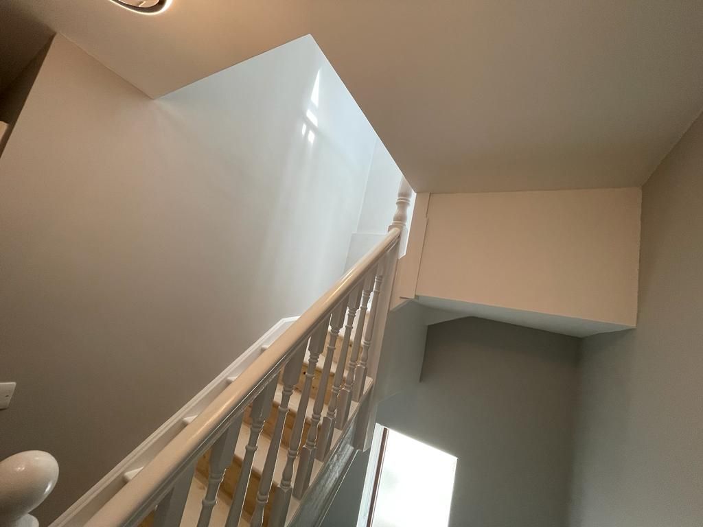Looking up at a staircase with a white railing and a window.