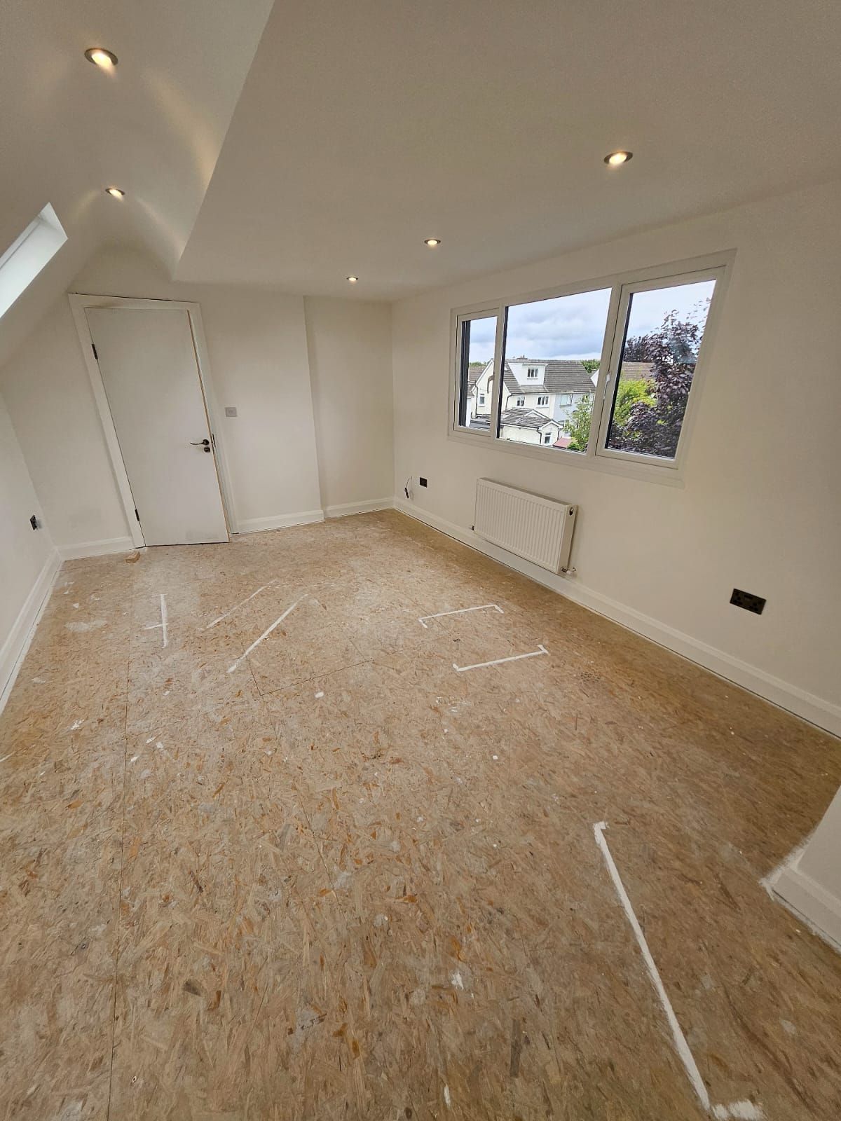 An empty room with a wooden floor and white walls.