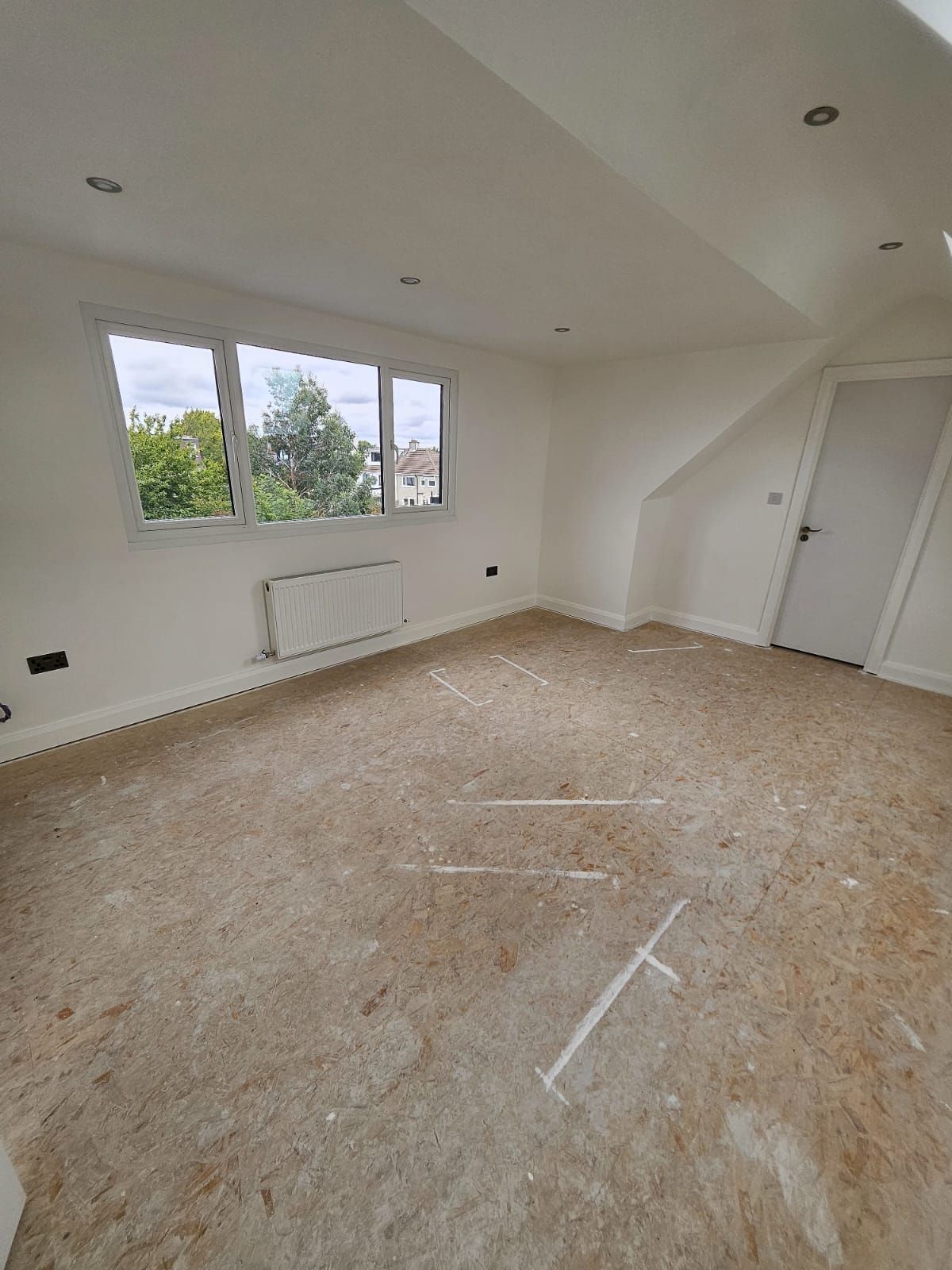 An empty room with a carpeted floor and a window.