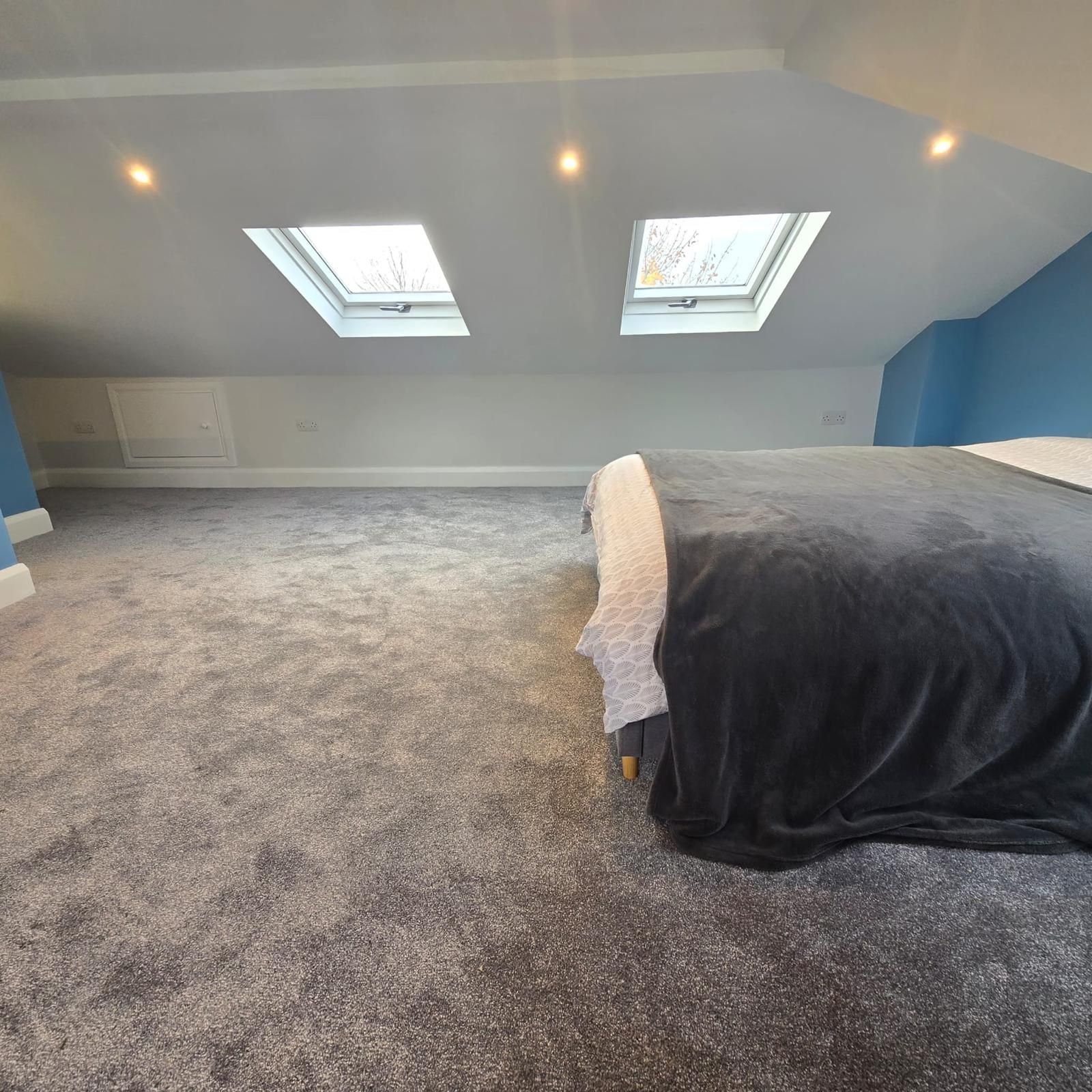 A bedroom with a bed and two skylights on the ceiling