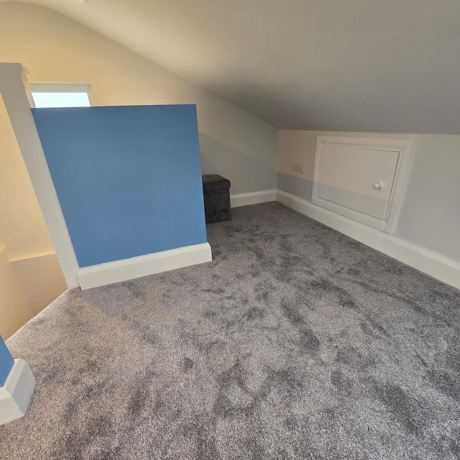 A room with a blue wall and a gray carpet
