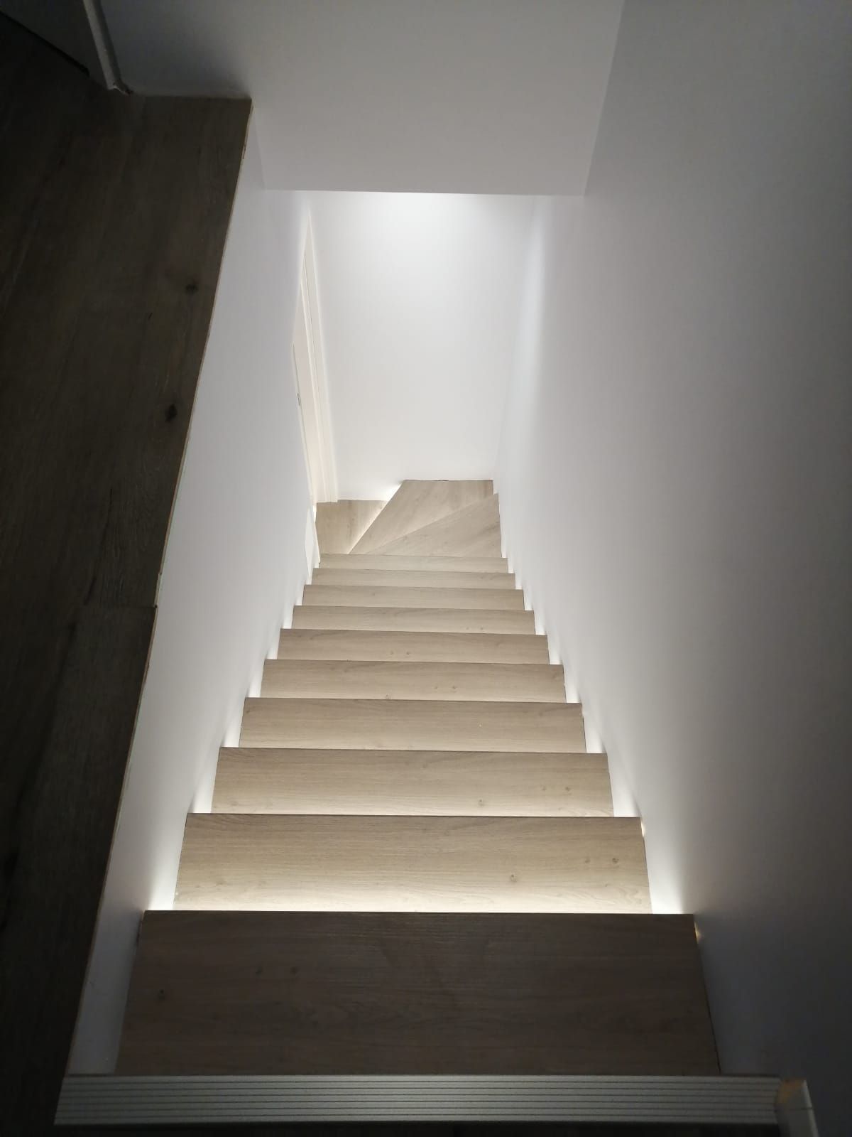A wooden staircase with a light on the steps