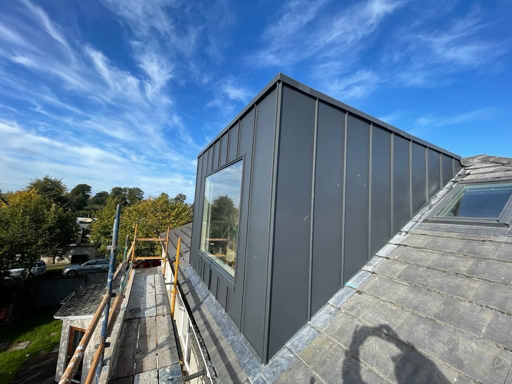 A roof with a window and scaffolding on it is being built.
