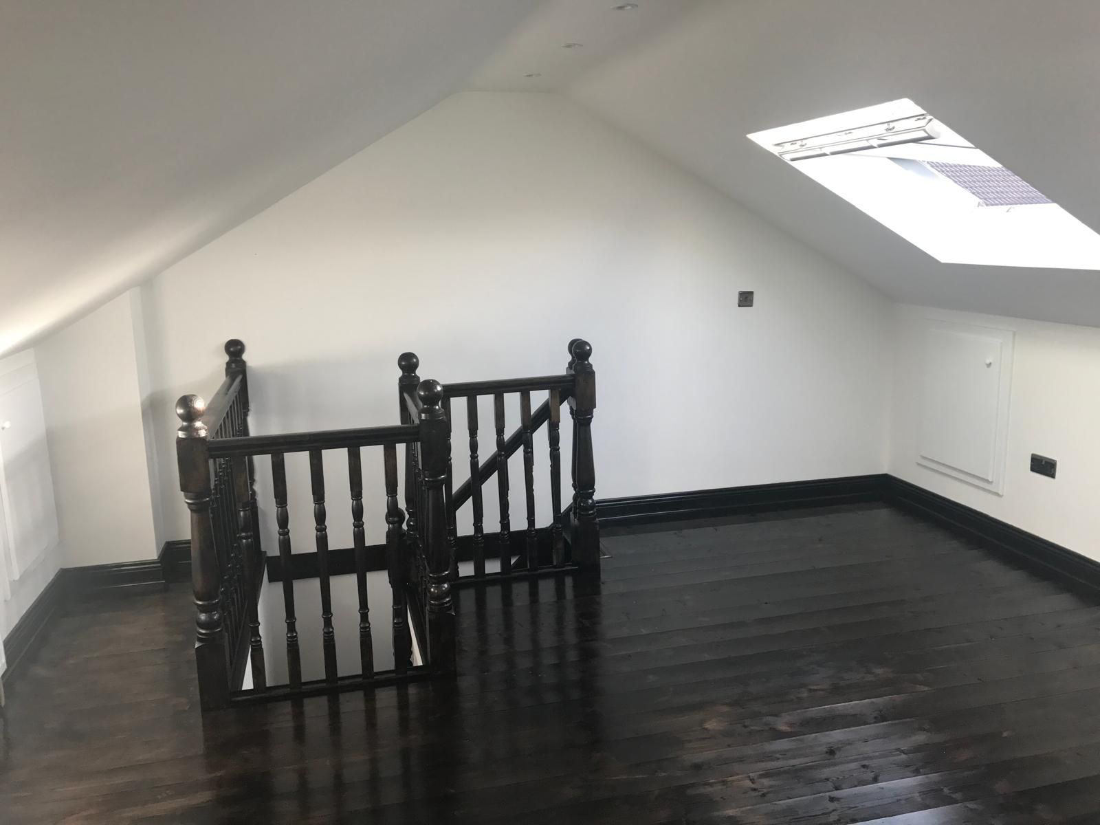 An empty room with a staircase and a skylight.