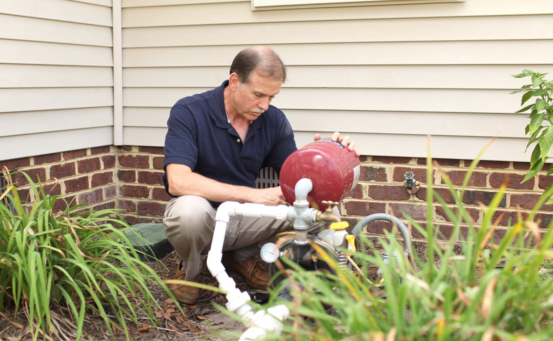 Worker repairing a well pump system, highlighting Mastery Plumbing's expertise in well pump system r