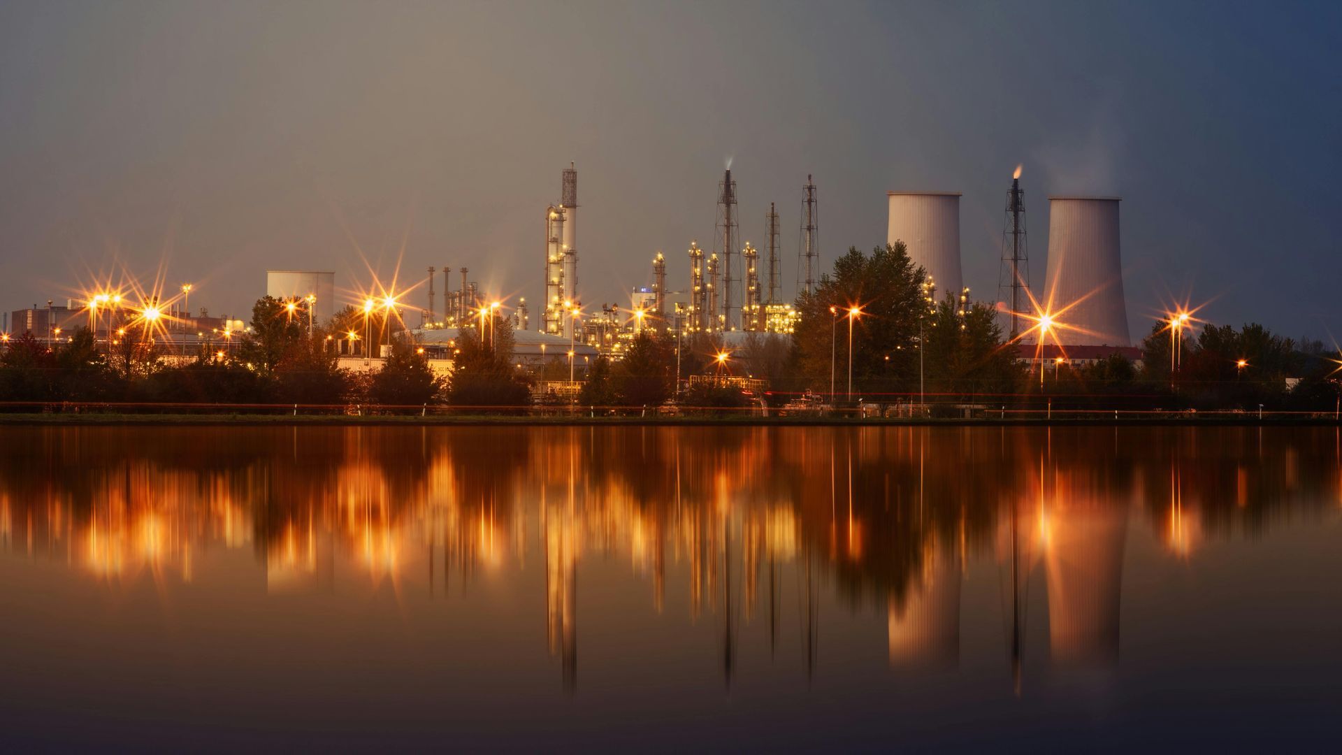 A large factory is reflected in the water at night.