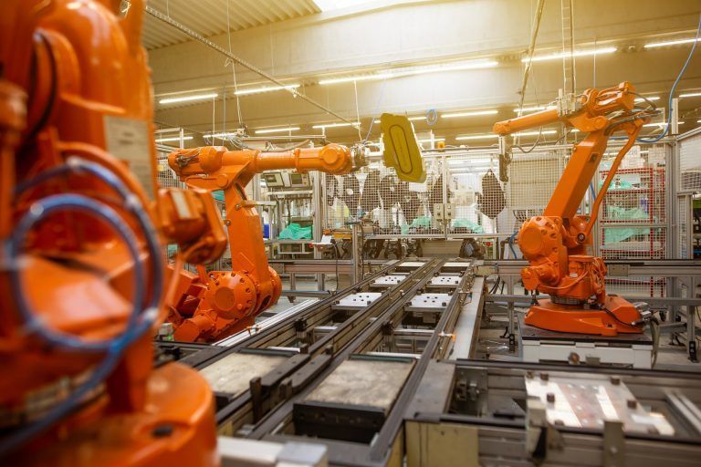 A bunch of orange robots are sitting on a conveyor belt in a factory.