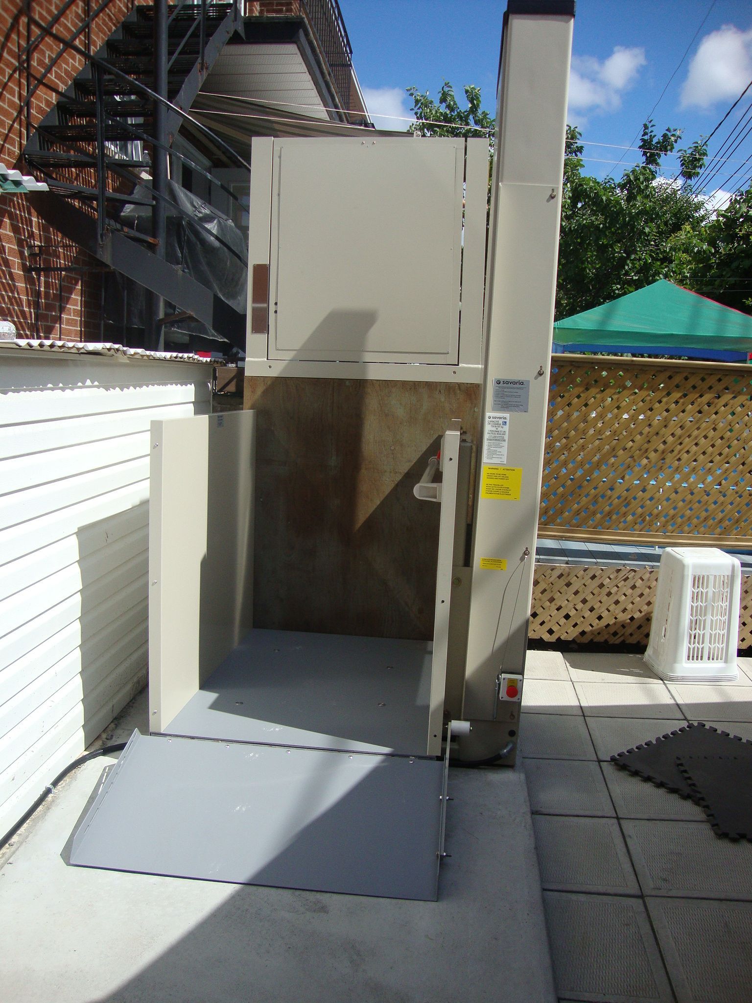 Élévateur extérieur pour fauteuil roulant sur une terrasse, structure métallique beige avec plateforme ouverte.