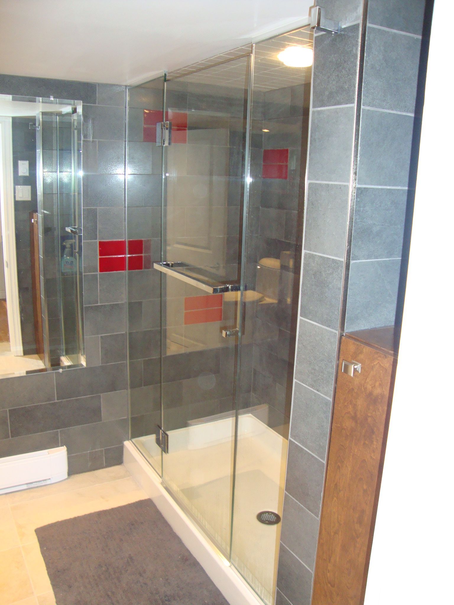 Cabine de douche en verre dans une salle de bains carrelée.