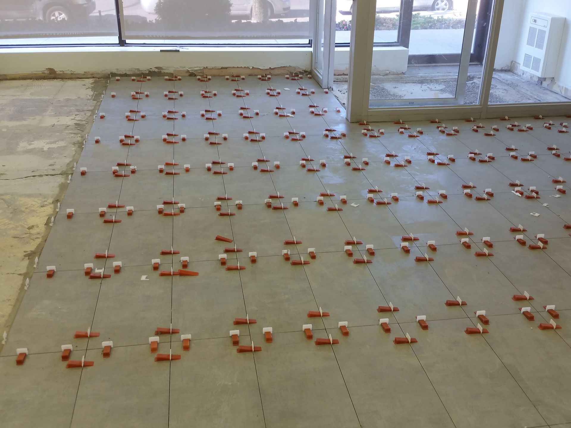 Carrelage de sol avec des croisillons orange disposés en grille, probablement lors de la pose.