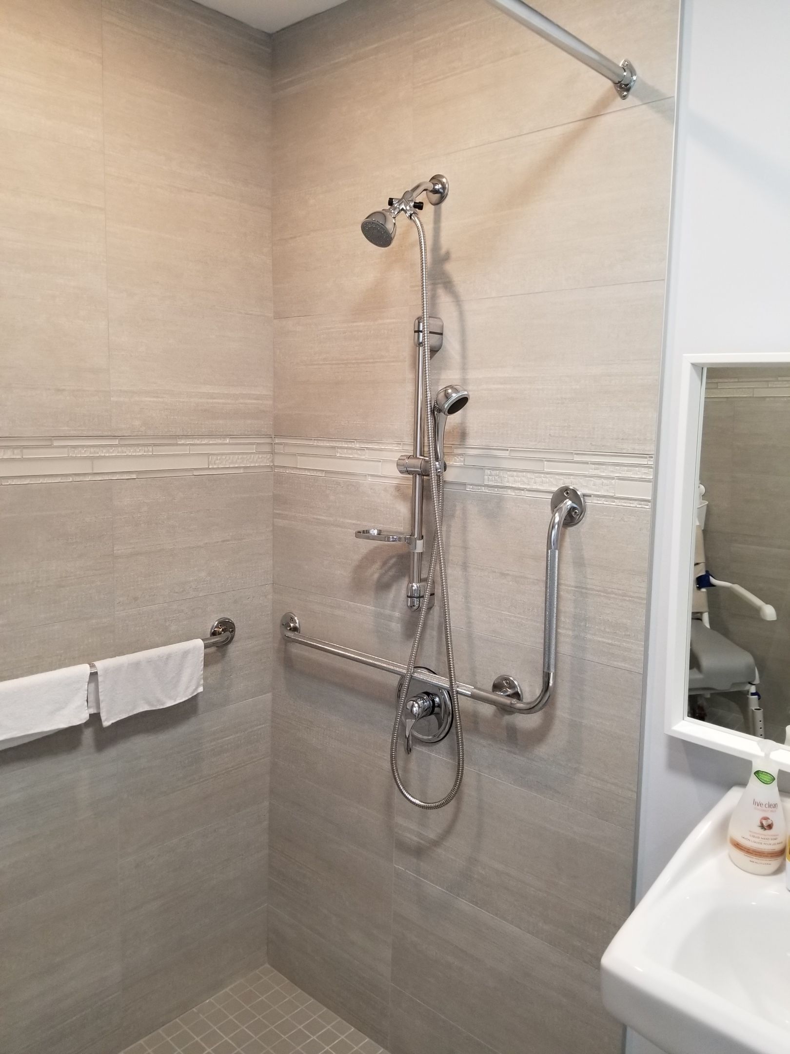 Douche accessible avec barres d'appui et pommeau de douche réglable.