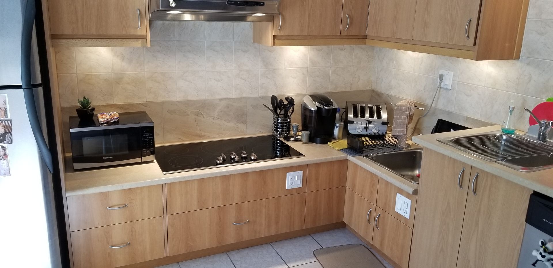 Cuisine avec placards en bois, appareils électroménagers comme micro-ondes, grille-pain et évier.