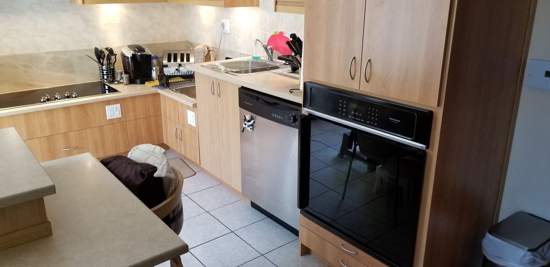 Cuisine avec placards et plans de travail en bois clair, et électroménager en inox. Four encastré.