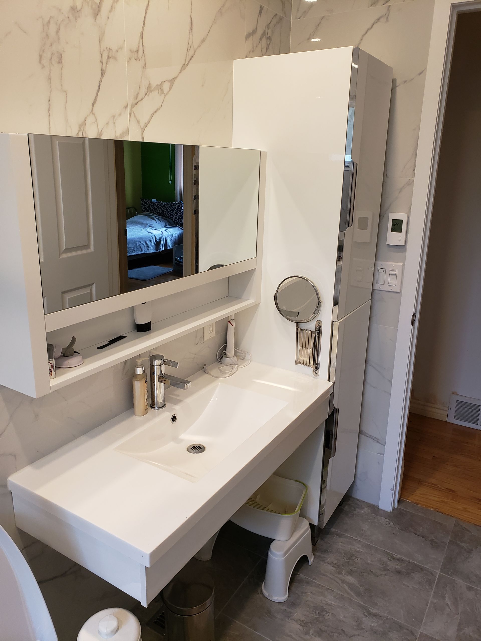 Salle de bains moderne blanche avec lavabo suspendu, meuble-lavabo, miroir et marchepied.