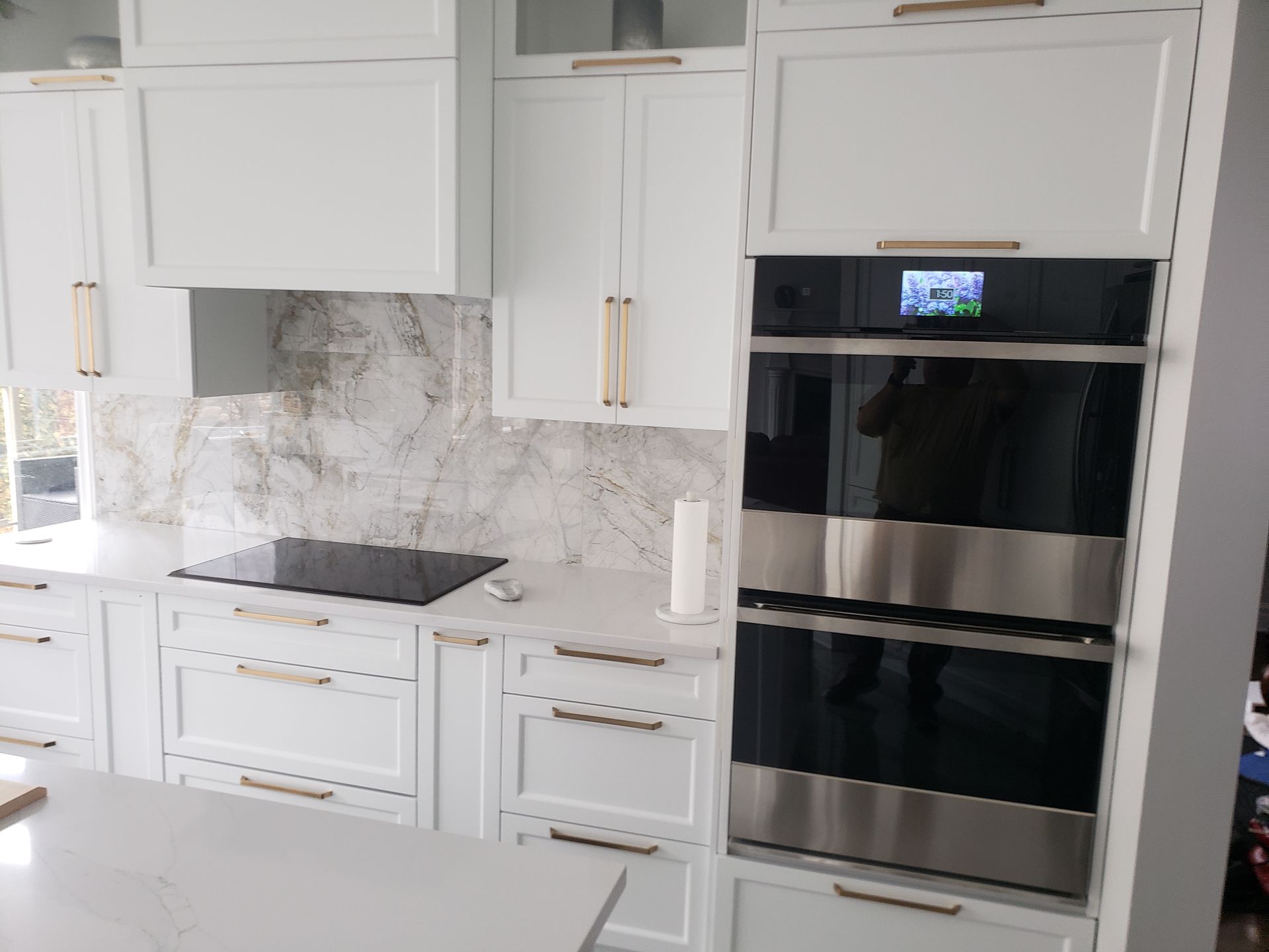 Cuisine équipée d'armoires blanches, de comptoirs clairs et d'un four double en acier inoxydable.