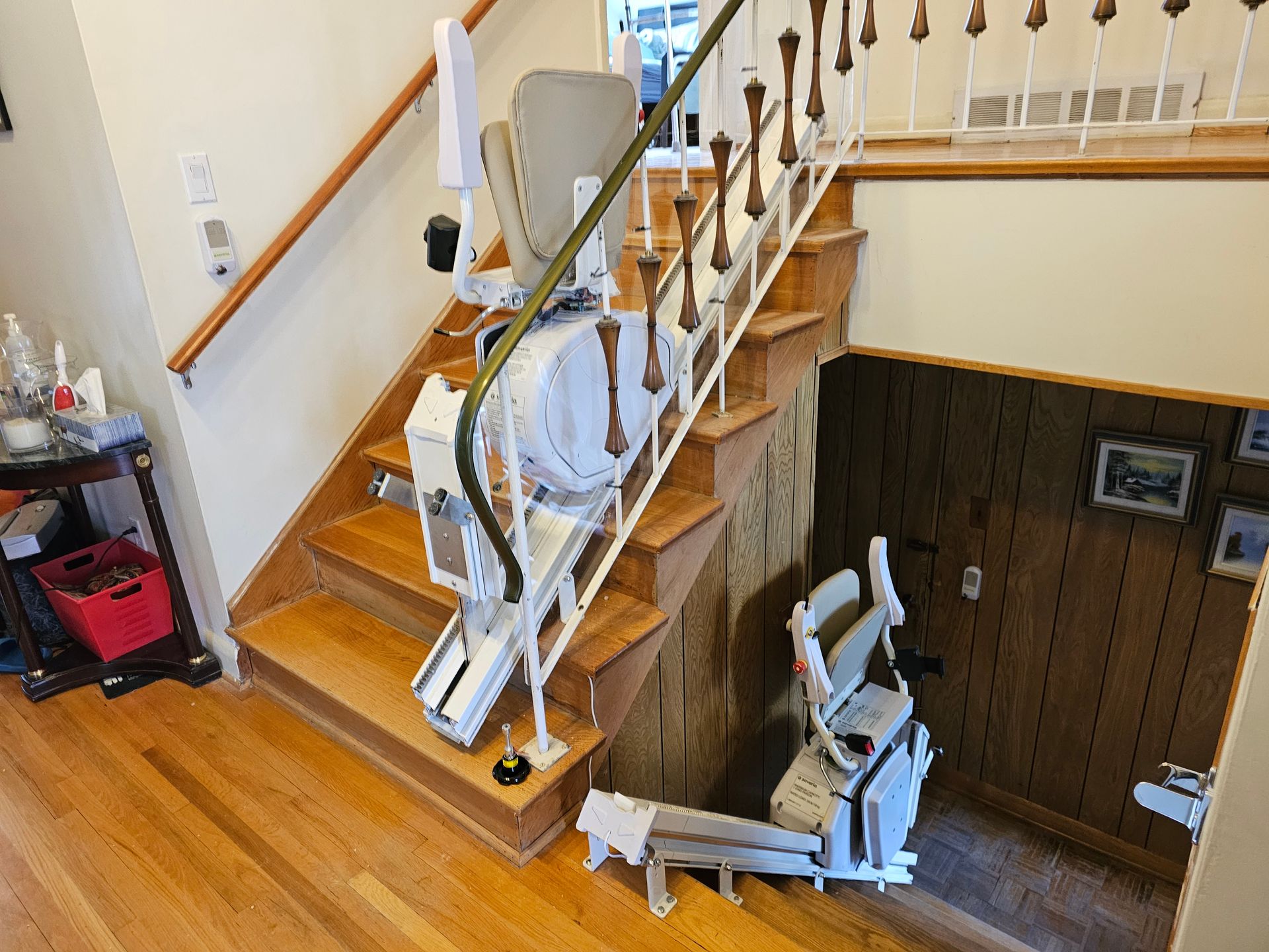 Monte-escalier sur un escalier en bois avec siège en haut et en bas, dans un intérieur de maison.