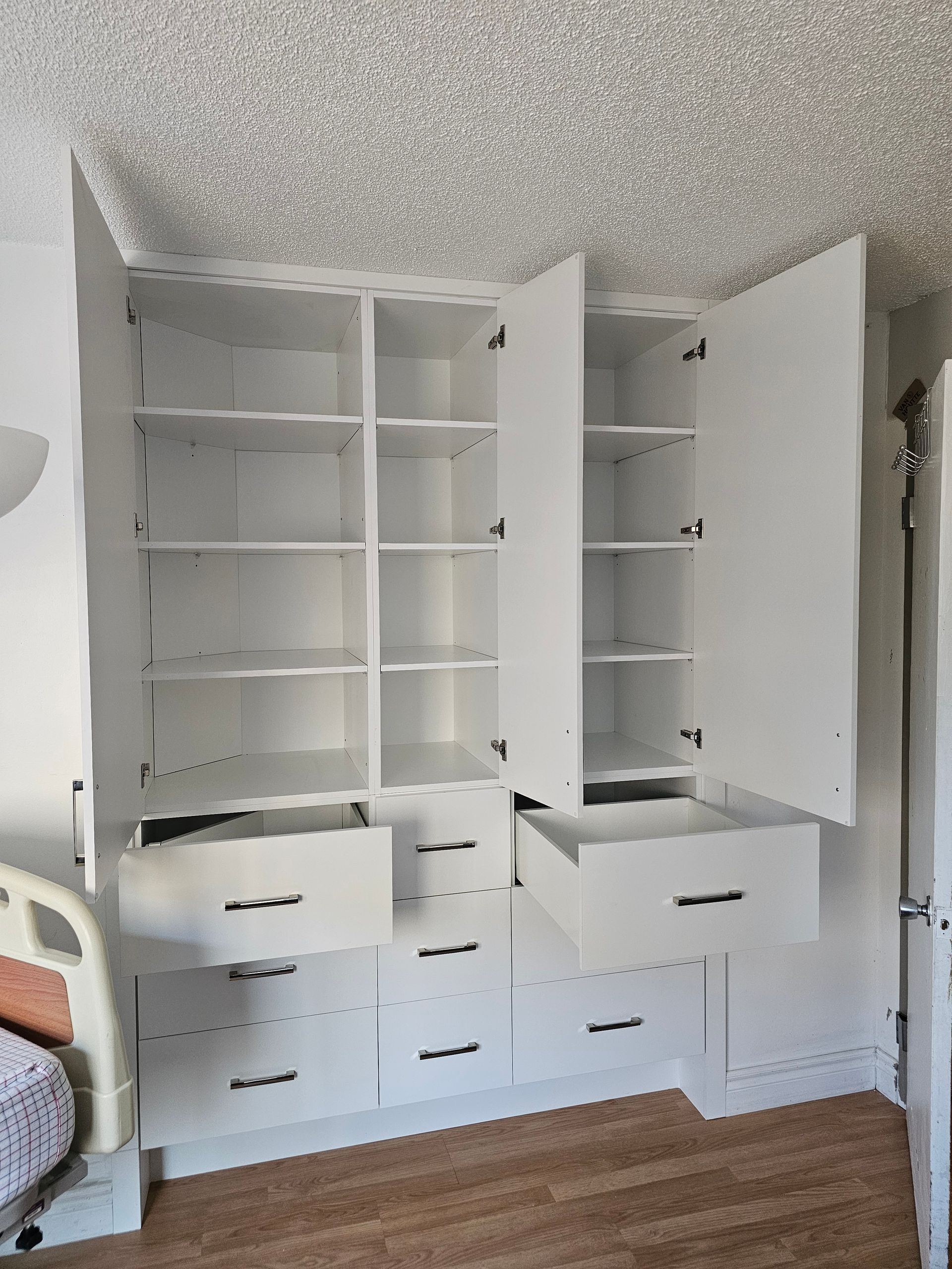 Meuble de rangement encastré blanc avec portes et tiroirs ouverts ; étagères et poignées visibles.