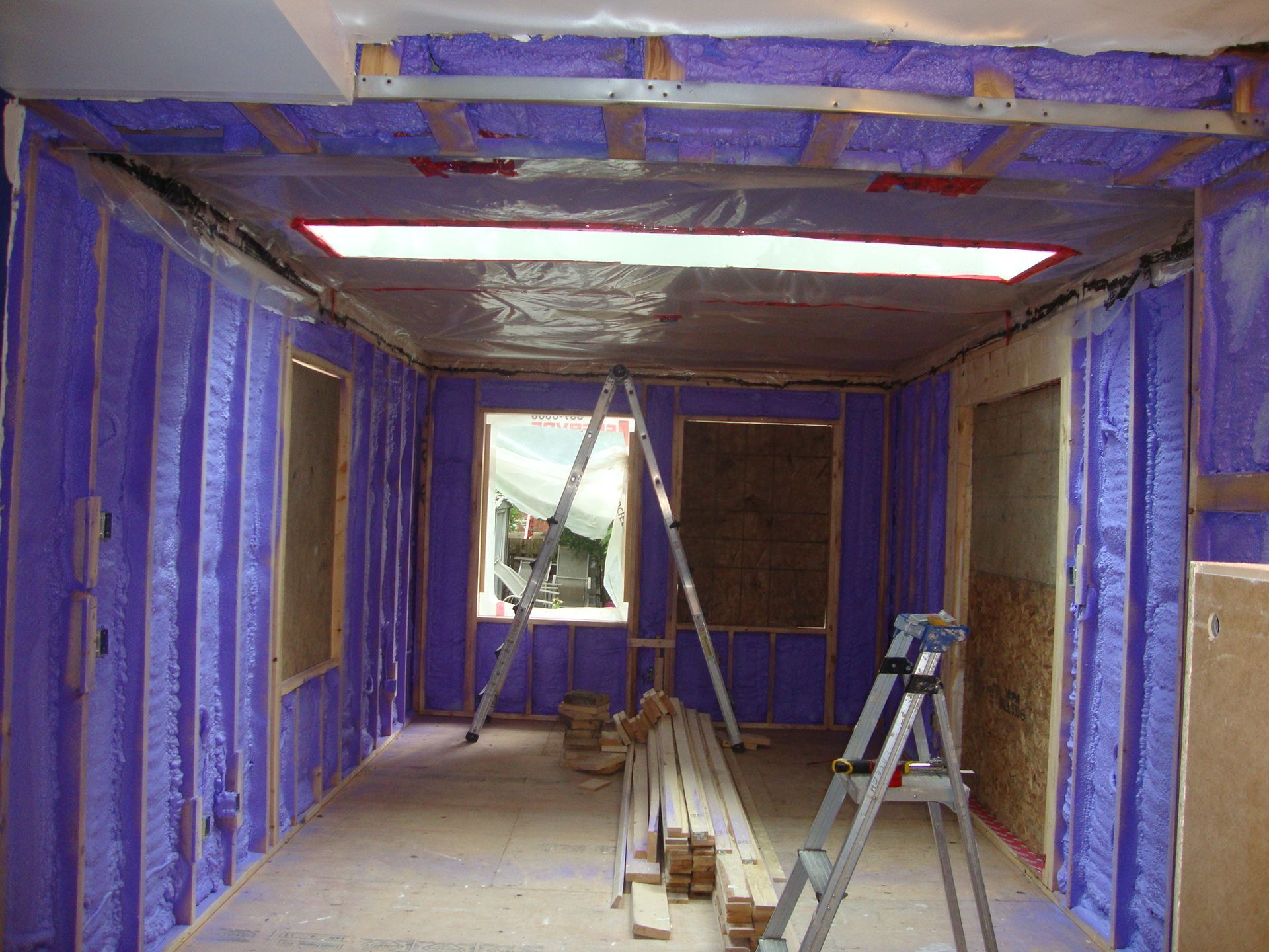 Intérieur d'une pièce en construction avec isolation violette sur les murs et le plafond.