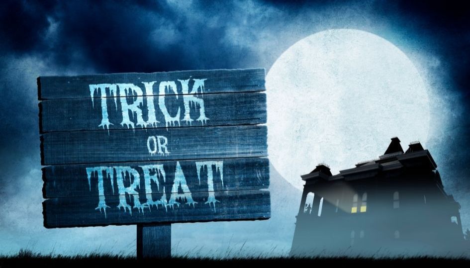 Spooky haunted halloween house dark cloudy skies full moon and trick or treat sign.