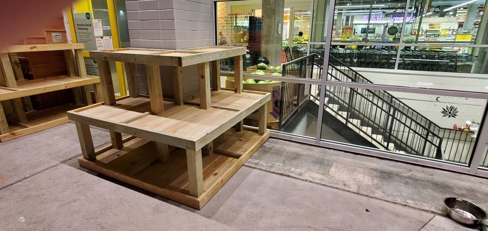 Wooden tiered display structures with glass windows in the background. A set of stairs is visible, and a bowl sits near the window.