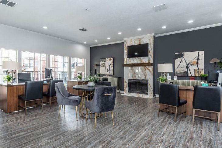 An office lobby with desks and chairs, a fireplace, and a round table.