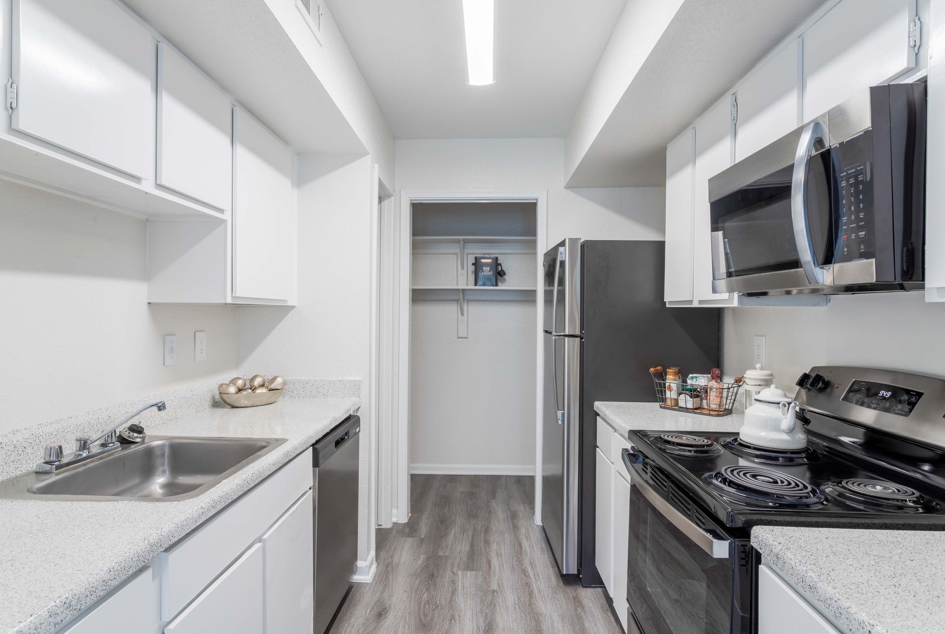 Bedroom with gray walls, bed, and nightstand with lamp. Window and ceiling fan visible.