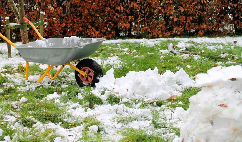 A wheelbarrow is sitting in the snow next to a pile of snow.