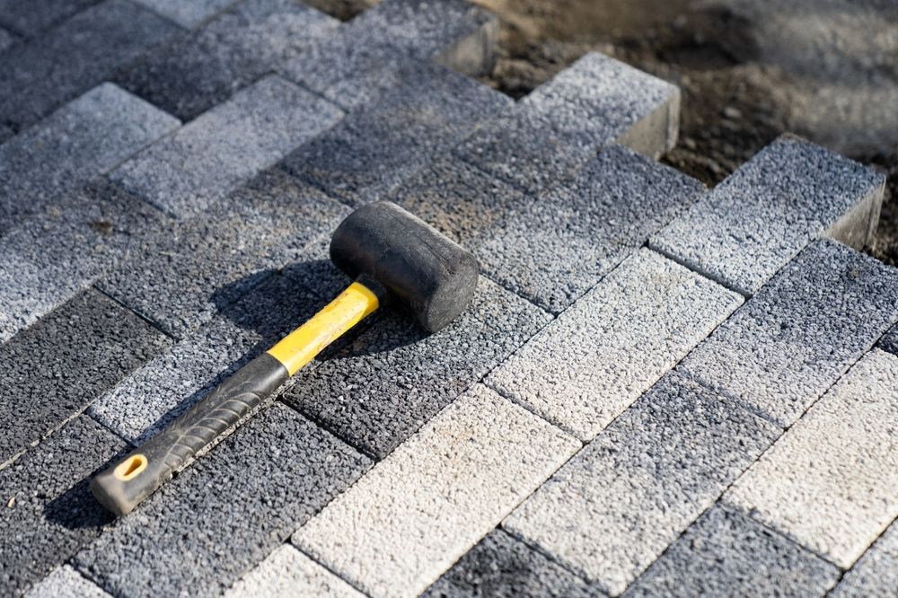A rubber mallet is sitting on top of a brick walkway.