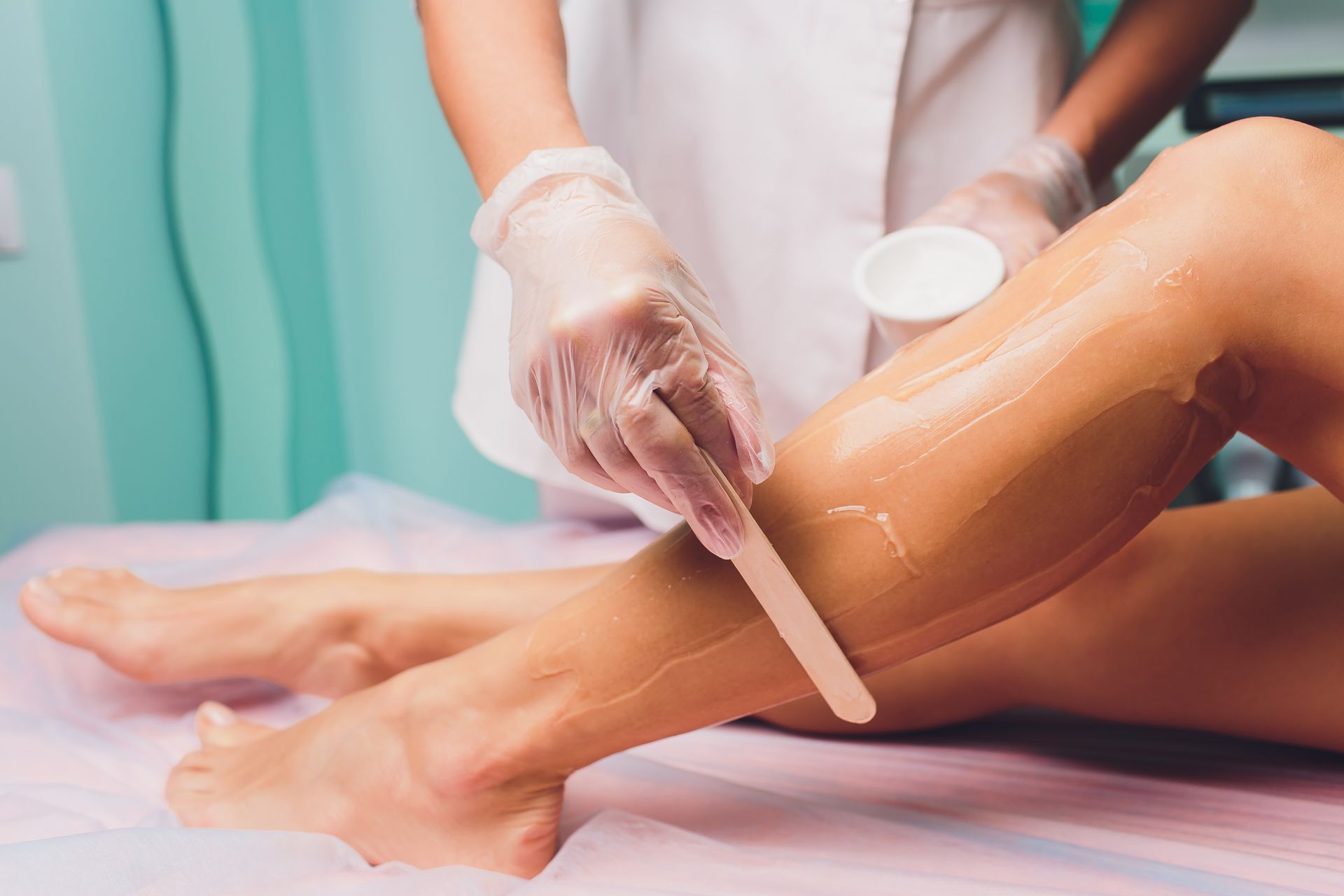 A woman is getting her legs waxed in a beauty salon. 