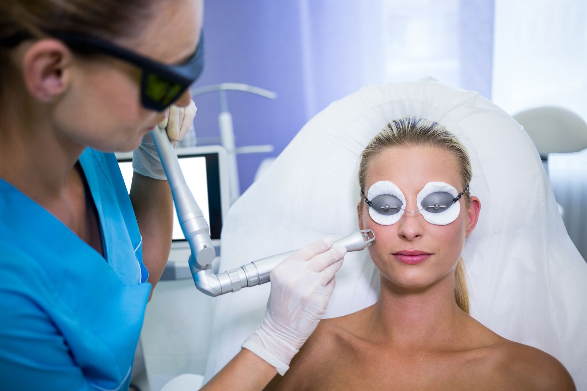 A woman is getting a laser treatment on her face. 