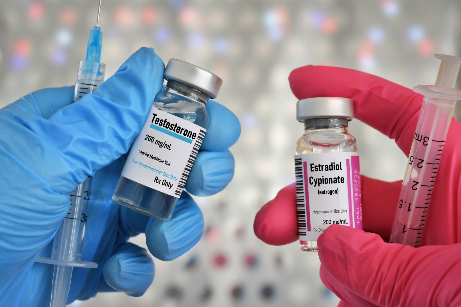 A person wearing pink gloves is holding two bottles of vaccine and a syringe. 