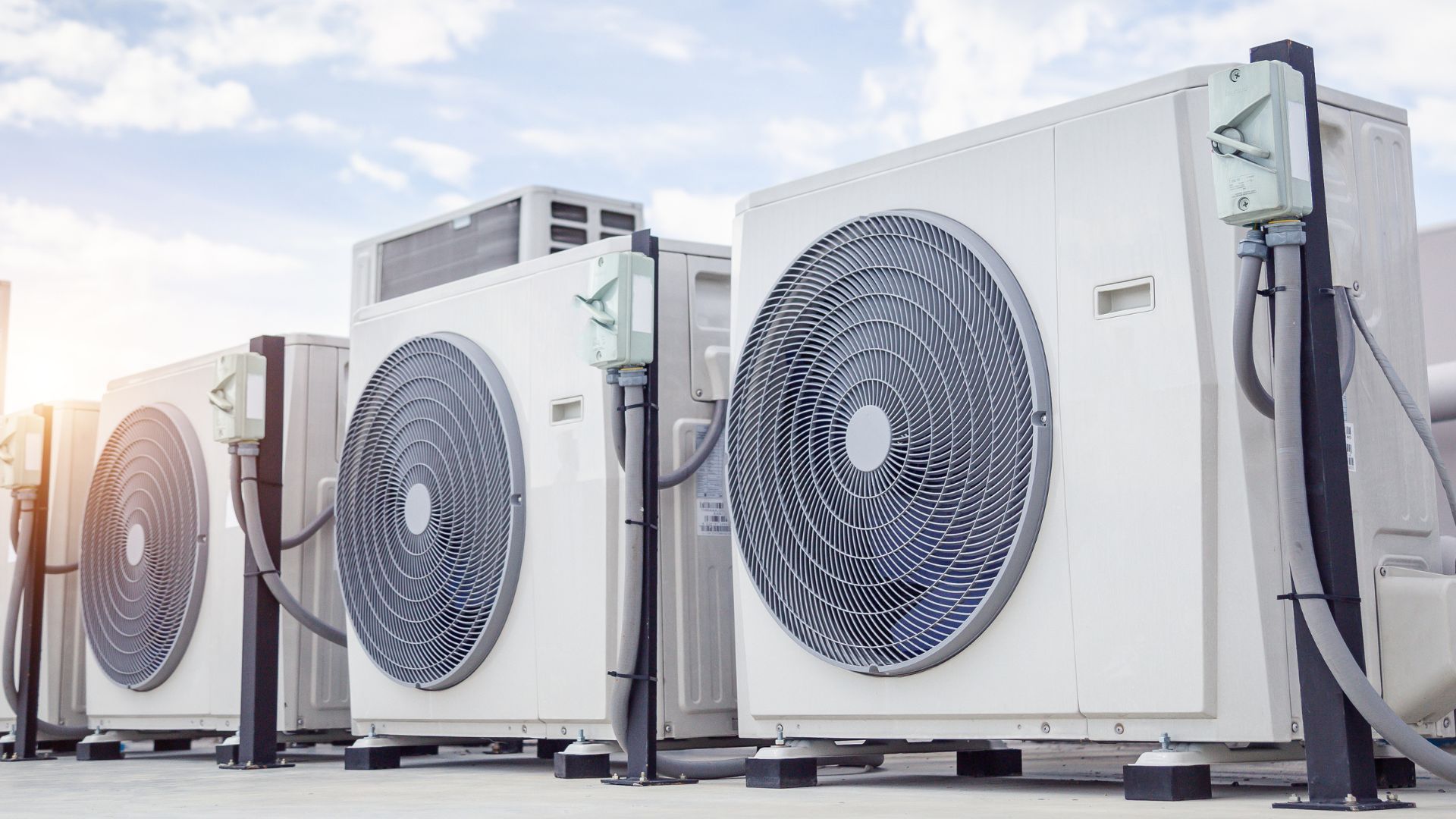 A row of air conditioners sitting next to each other on top of a building.