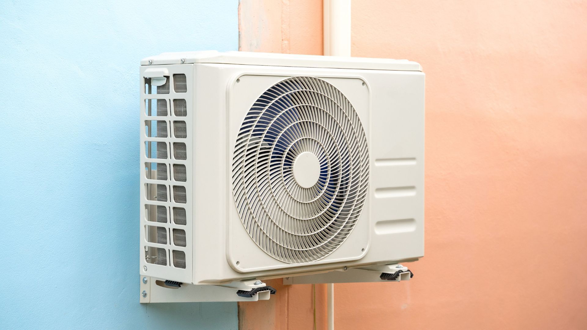 A white air conditioner is mounted on the side of a building.