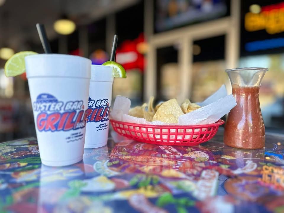 Two drinks with lime, chips with salsa, in a restaurant.