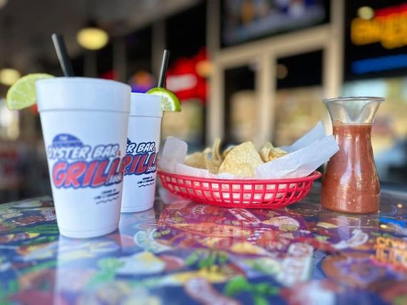 Two drinks with lime, chips with salsa, in a restaurant.