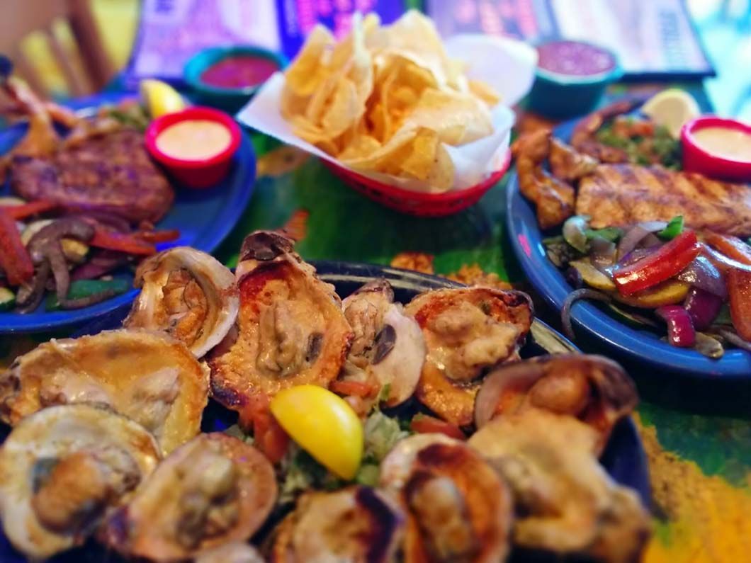 Assorted seafood and chips with dips served on blue plates at a restaurant table.