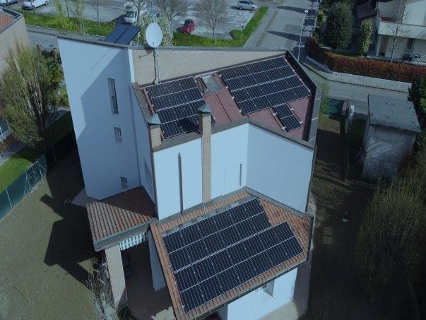 Pannelli solari su un edificio bianco a più piani con tetto di tegole marroni.
