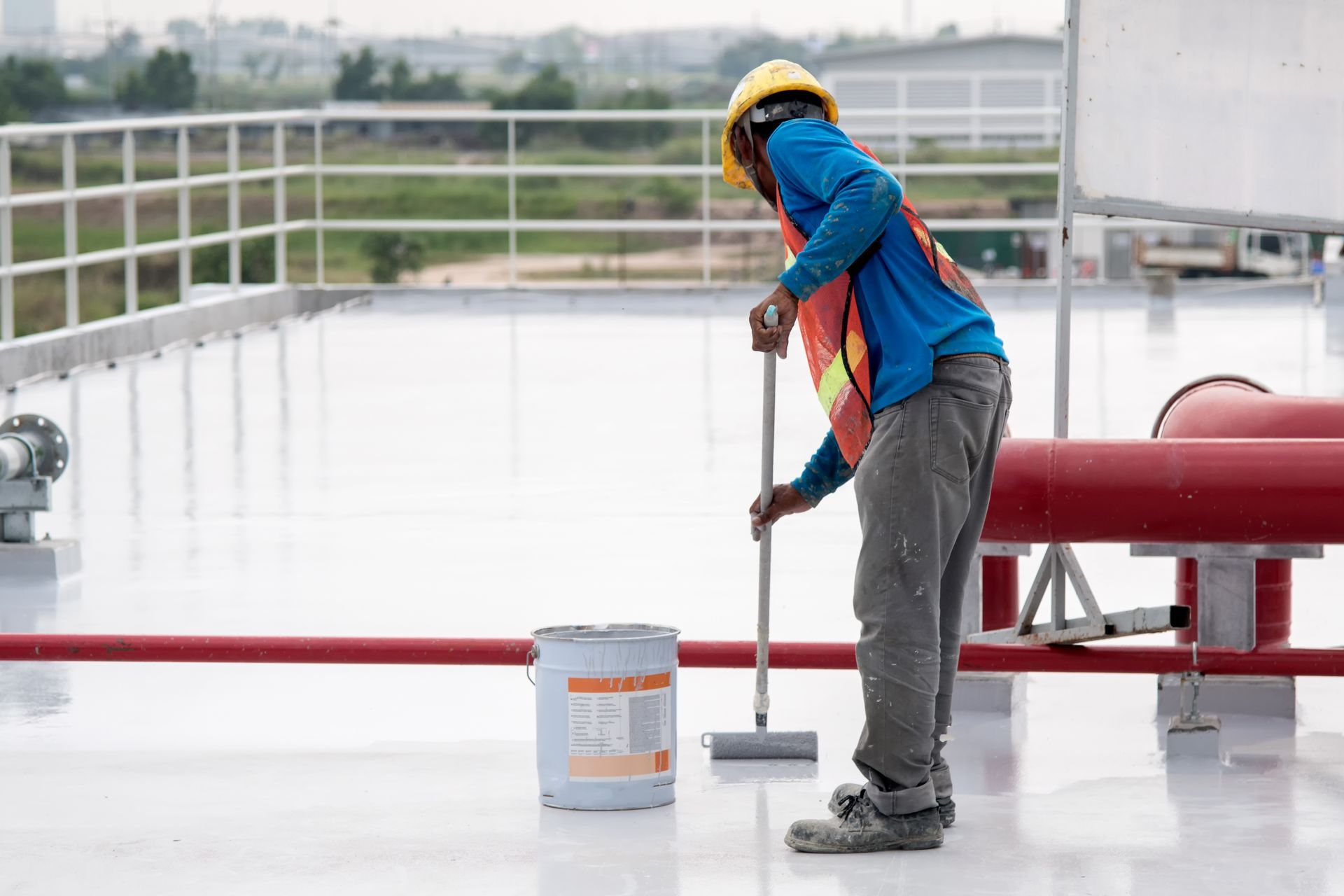 Construction worker coating epoxy paint at roof slab for water proof protection.