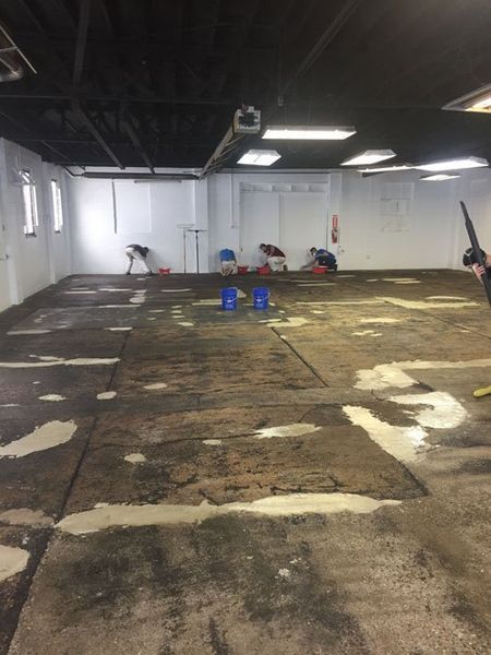 A person is cleaning the floor of a building with a vacuum cleaner.