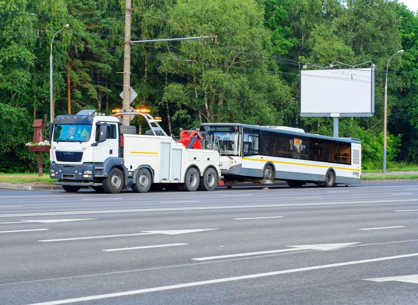 A tow truck is towing a bus on the street.