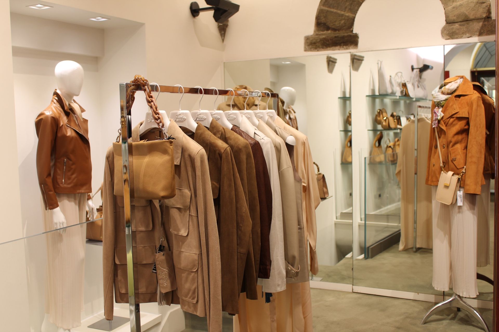 Un negozio con vestiti appesi su rastrelliere e manichini davanti a uno specchio.