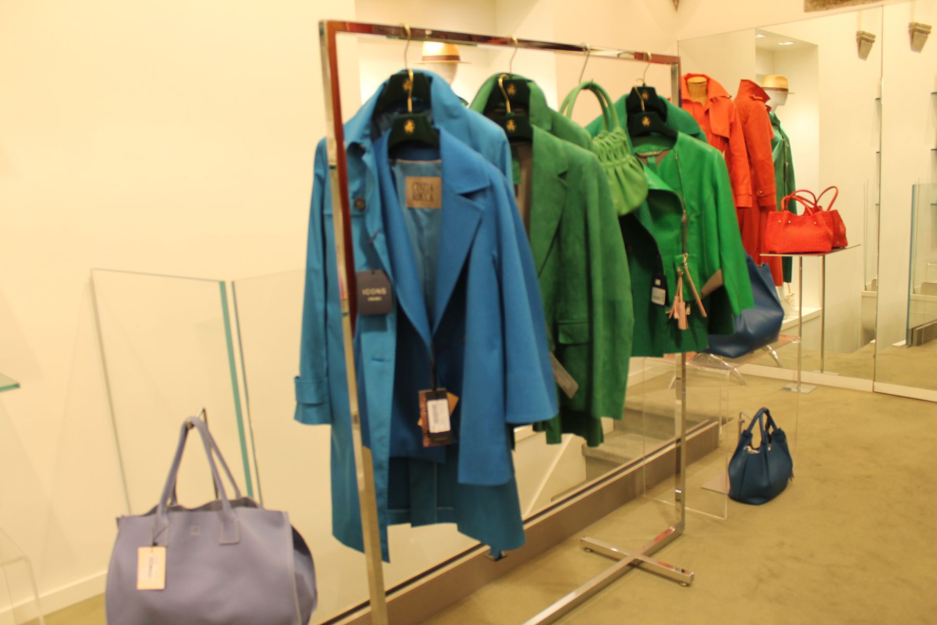 Una fila di cappotti blu e verdi appesi a un attaccapanni