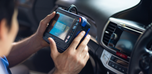 A technician holds a diagnostic scan tool inside a vehicle, reviewing data on the screen. | Airpark Auto Pros