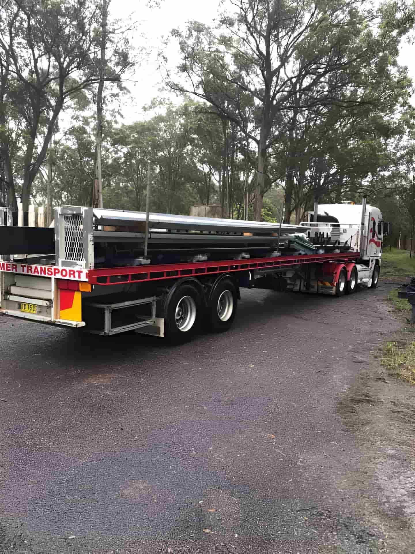 A Semi Truck Is Carrying A Large Pipe On A Trailer — Primmer Steel In Forster, NSW
