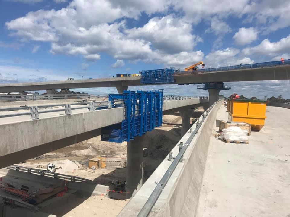 A Bridge Under Construction With A Blue Lift Attached To It — Primmer Steel In Nabiac, NSW