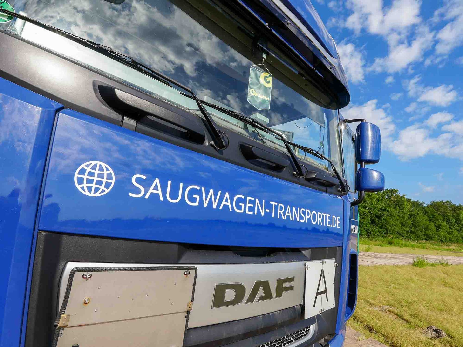 Ein blauer Saugtankwagen steht auf einem Feld.