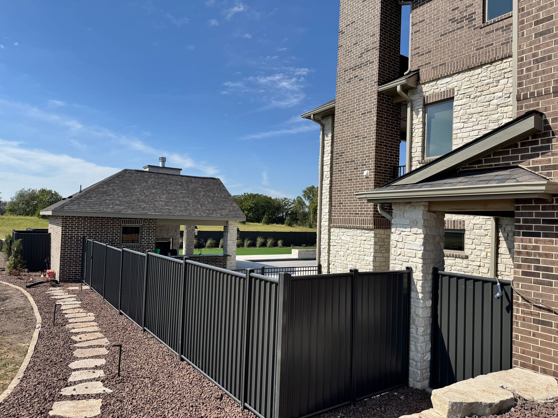 Black fence surrounds a pool with a slide.