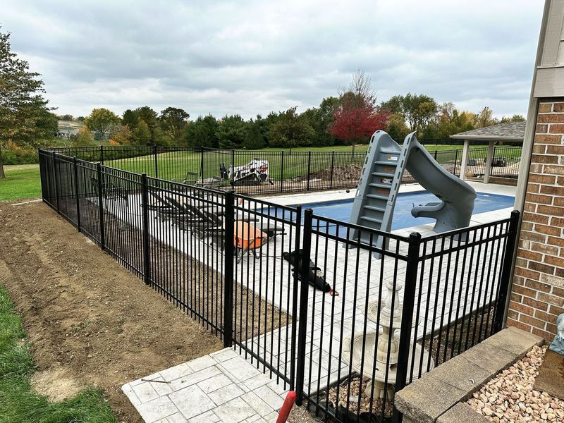 Black metal fence surrounding a pool with a slide.
