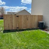 Wooden fence adjacent to a house, with an air conditioning unit visible.