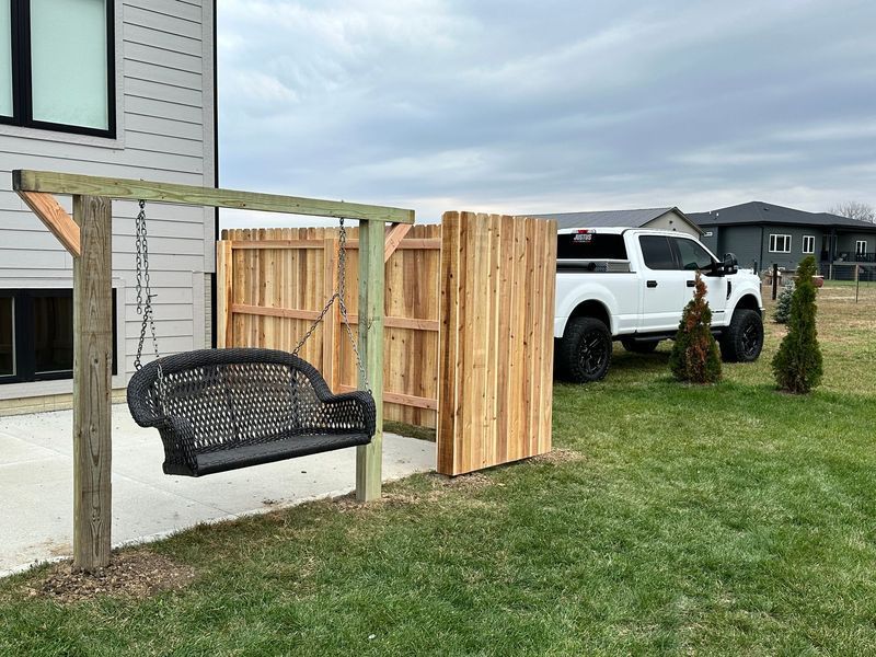 Swing set and wooden fence in a yard with a white truck.